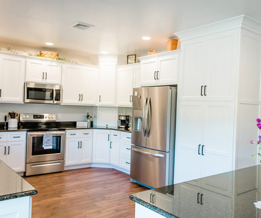 Kitchen trends featuring white cabinets, black hardware, granite countertops, and stainless-steel appliances.