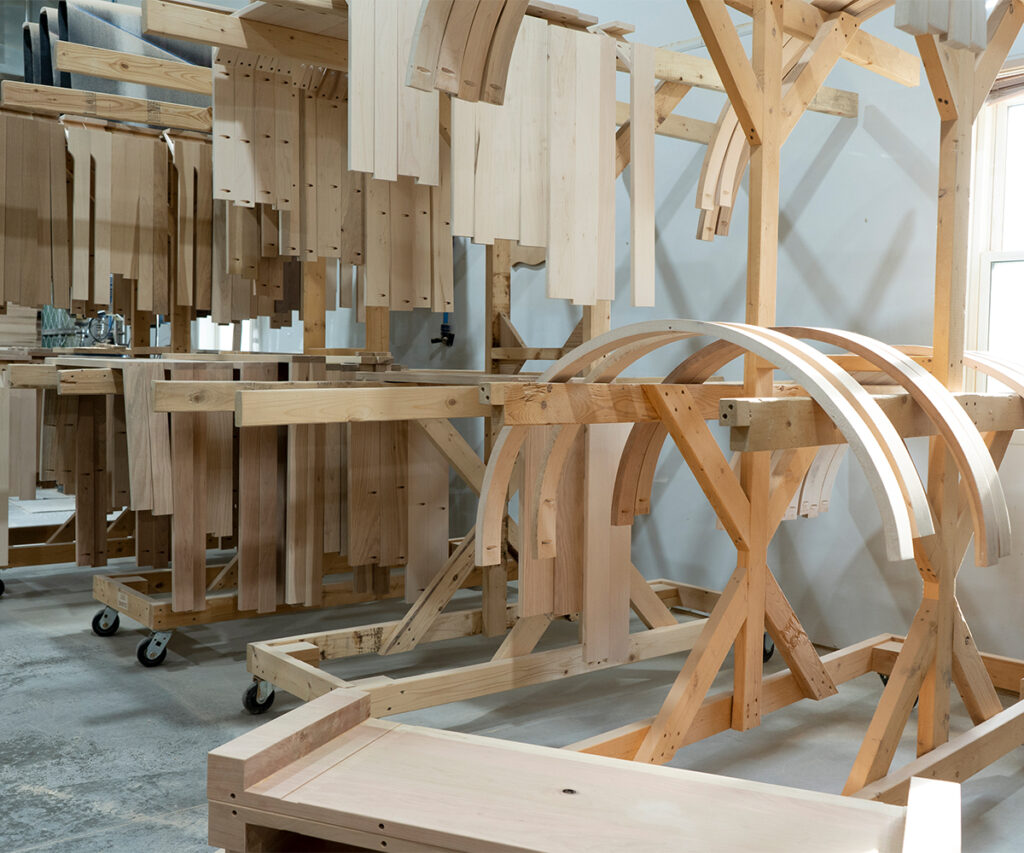Milled hardwood parts hanging on racks, ready for precise Amish furniture component assembly.