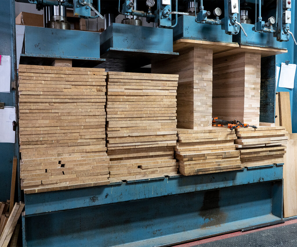 Stacked hardwood boards in press for drying and conditioning before Amish furniture building.